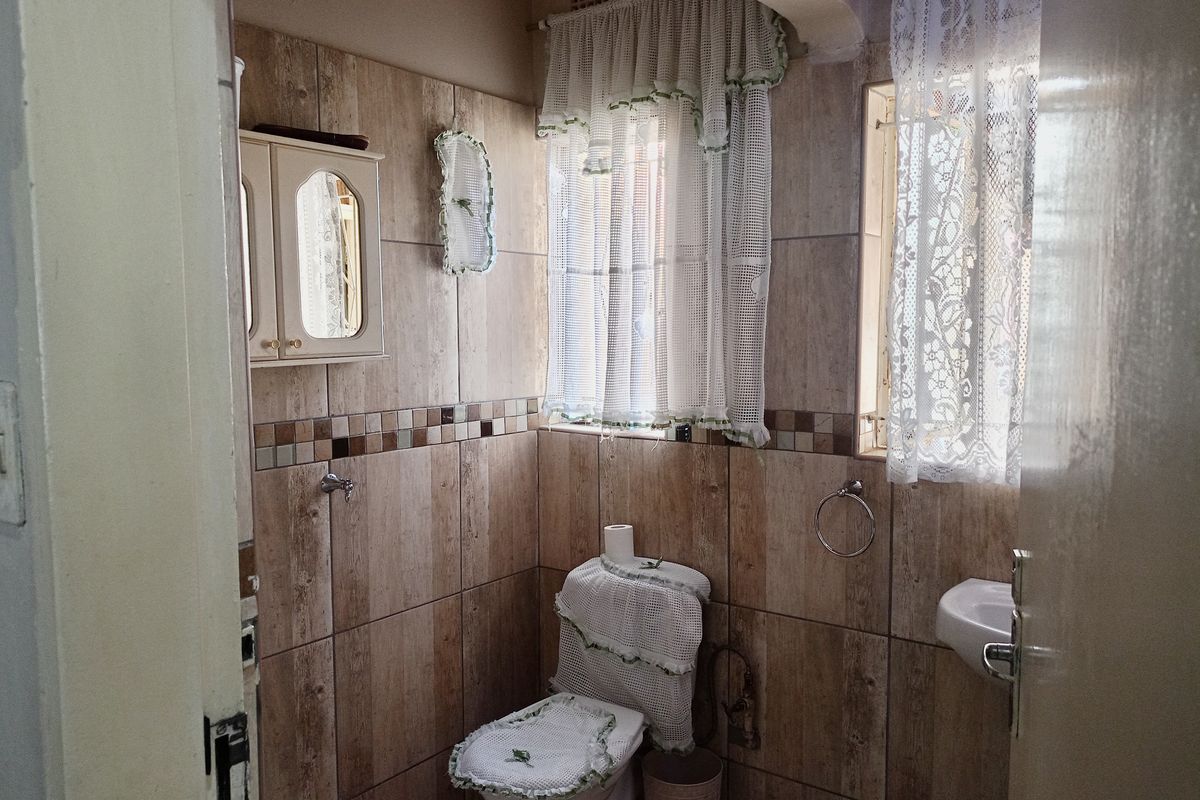 A compact bathroom featuring floor-to-ceiling wood-look ceramic wall tiles, a wall-mounted basin, and a standard toilet.