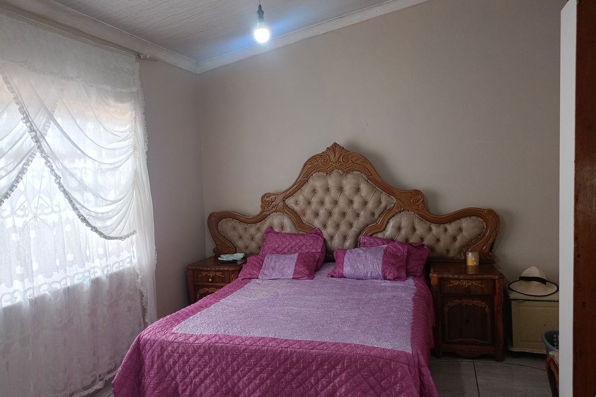 A bedroom featuring tiled flooring and a textured ceiling, providing a functional space for rest.