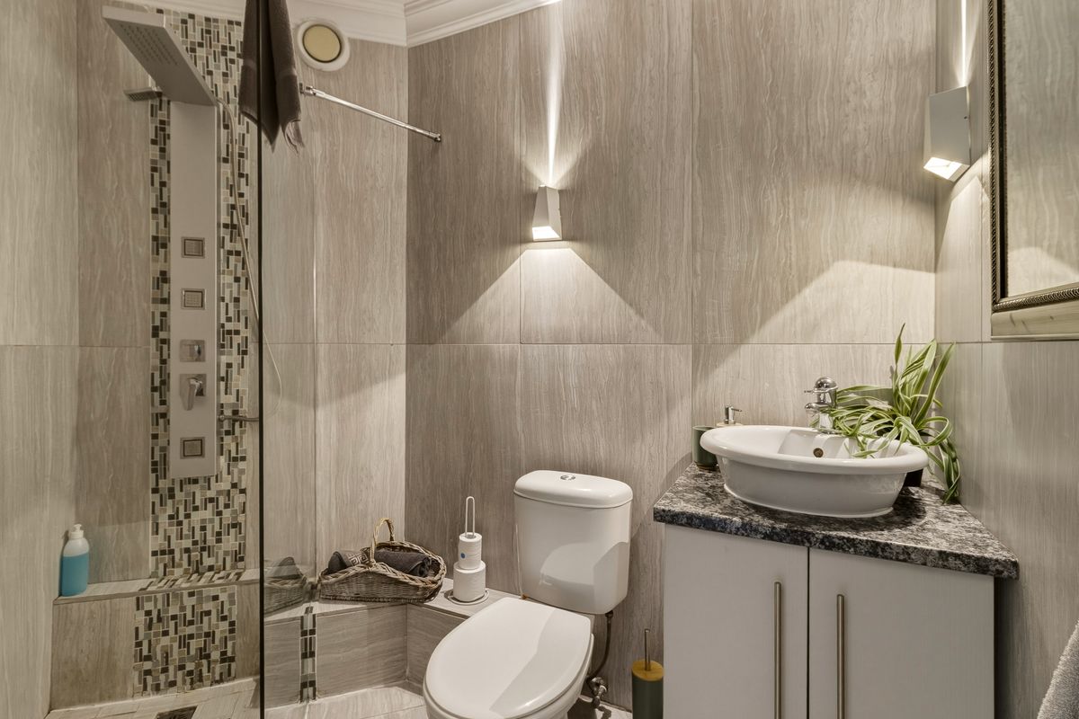 Modern bathroom featuring a glass-enclosed shower with a mosaic tile accent, a vessel sink on a granite vanity, and contemporary wall lighting.