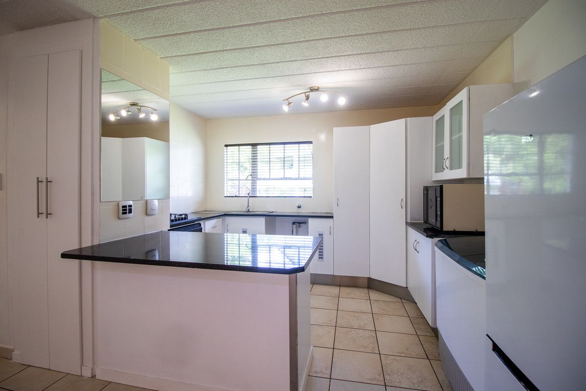 A functional kitchen featuring granite countertops, ample built-in cabinetry, a double sink, and tiled flooring, offering a clean and practical workspace.