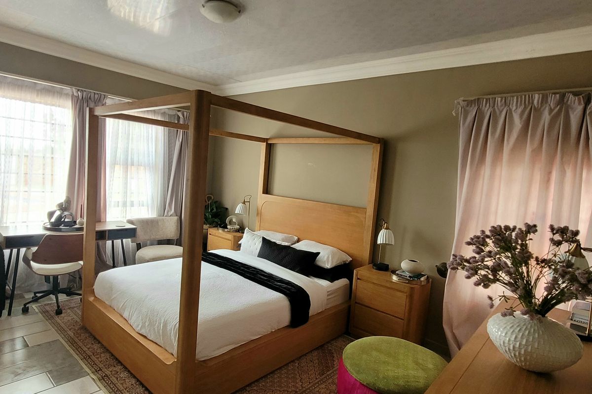 A well-lit bedroom featuring crown molding and tiled flooring, providing a comfortable and functional living space.