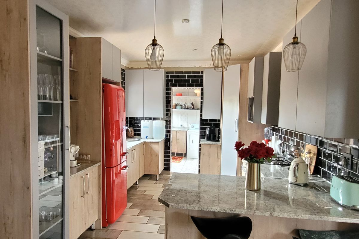 Modern kitchen featuring stone countertops, subway tile backsplash, pendant lighting, and ample built-in cabinetry with a functional breakfast bar layout.