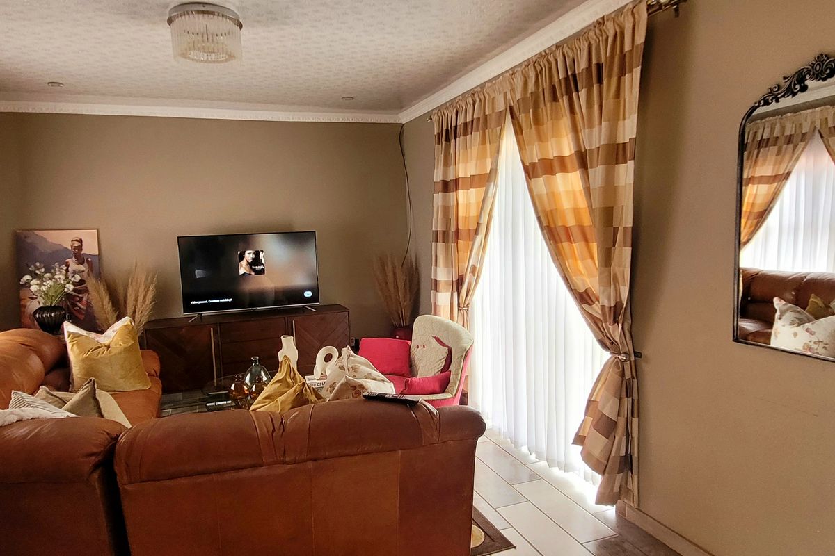 A comfortable living room featuring tiled flooring, crown molding, and recessed lighting, providing a functional and inviting space for relaxation.