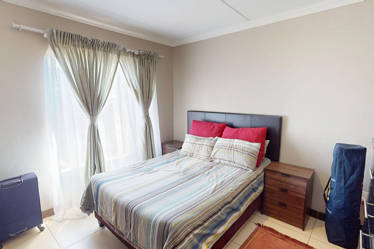 A functional bedroom featuring tiled flooring, neutral wall finishes, and large windows with installed curtain tracks.