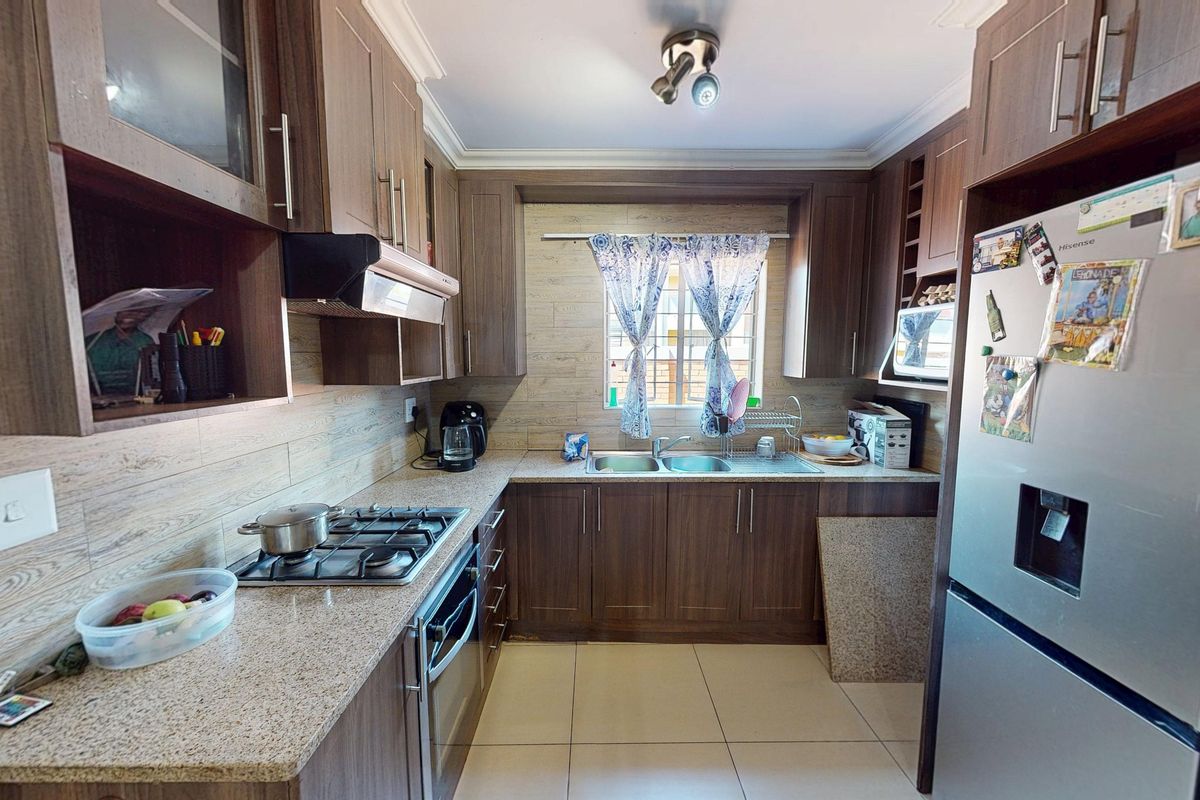 A functional kitchen featuring wood-finish cabinetry, granite countertops, a gas hob, and an integrated oven, providing a practical and well-organized cooking space.