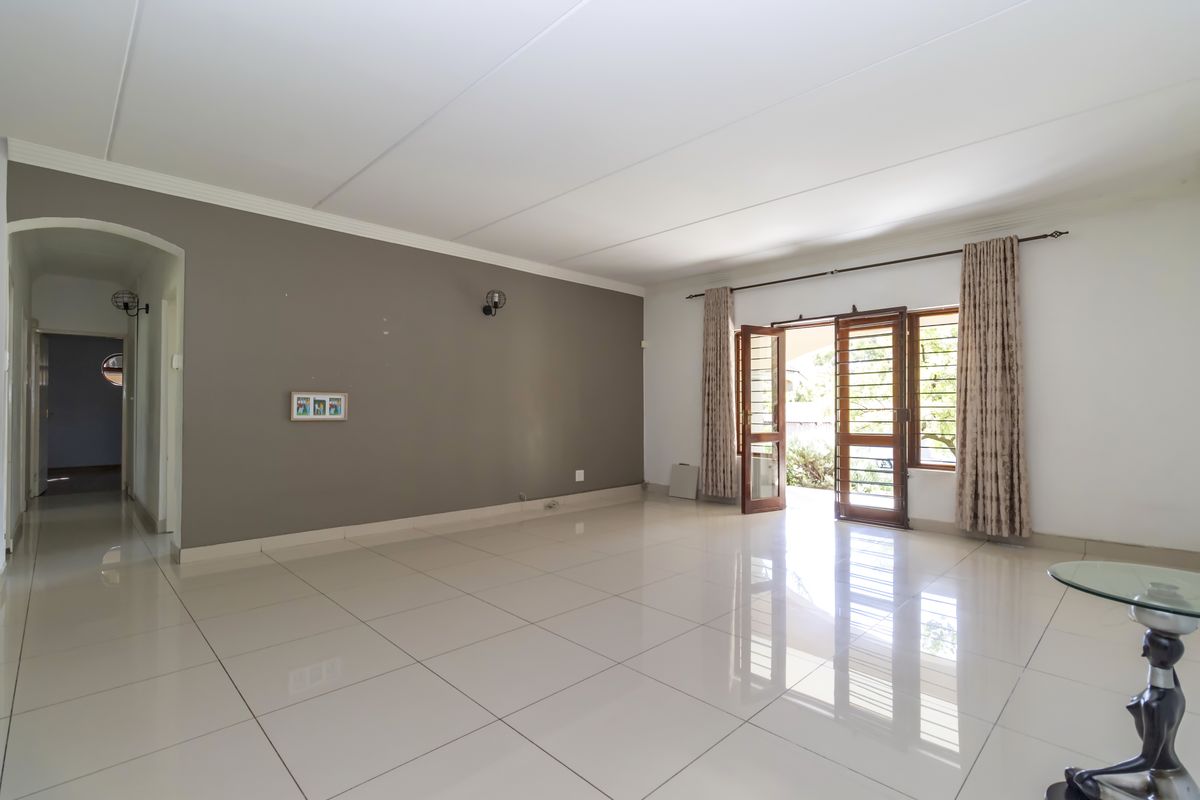 Spacious living area featuring polished floor tiles, neutral wall tones, and direct access to an outdoor patio through glass-paneled doors.