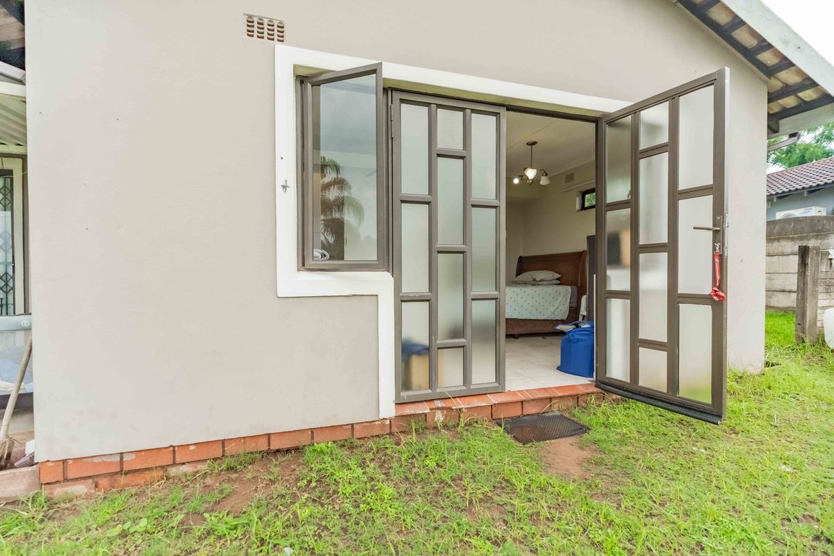 Rear exterior view of the property featuring aluminium framed glass doors and a brick plinth foundation.