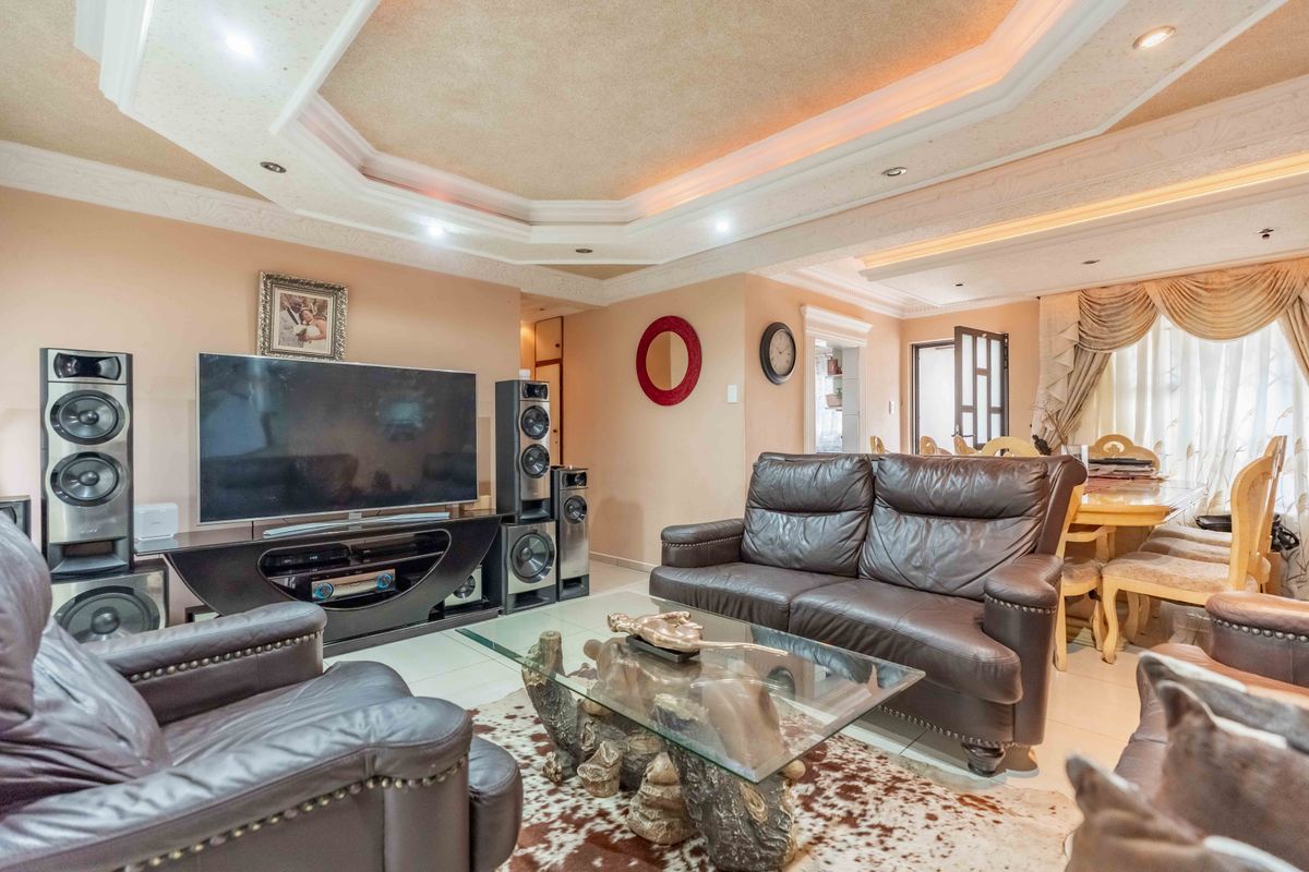 Spacious living room featuring a decorative recessed ceiling with integrated cove lighting and neutral tiled flooring, creating a warm and inviting atmosphere.