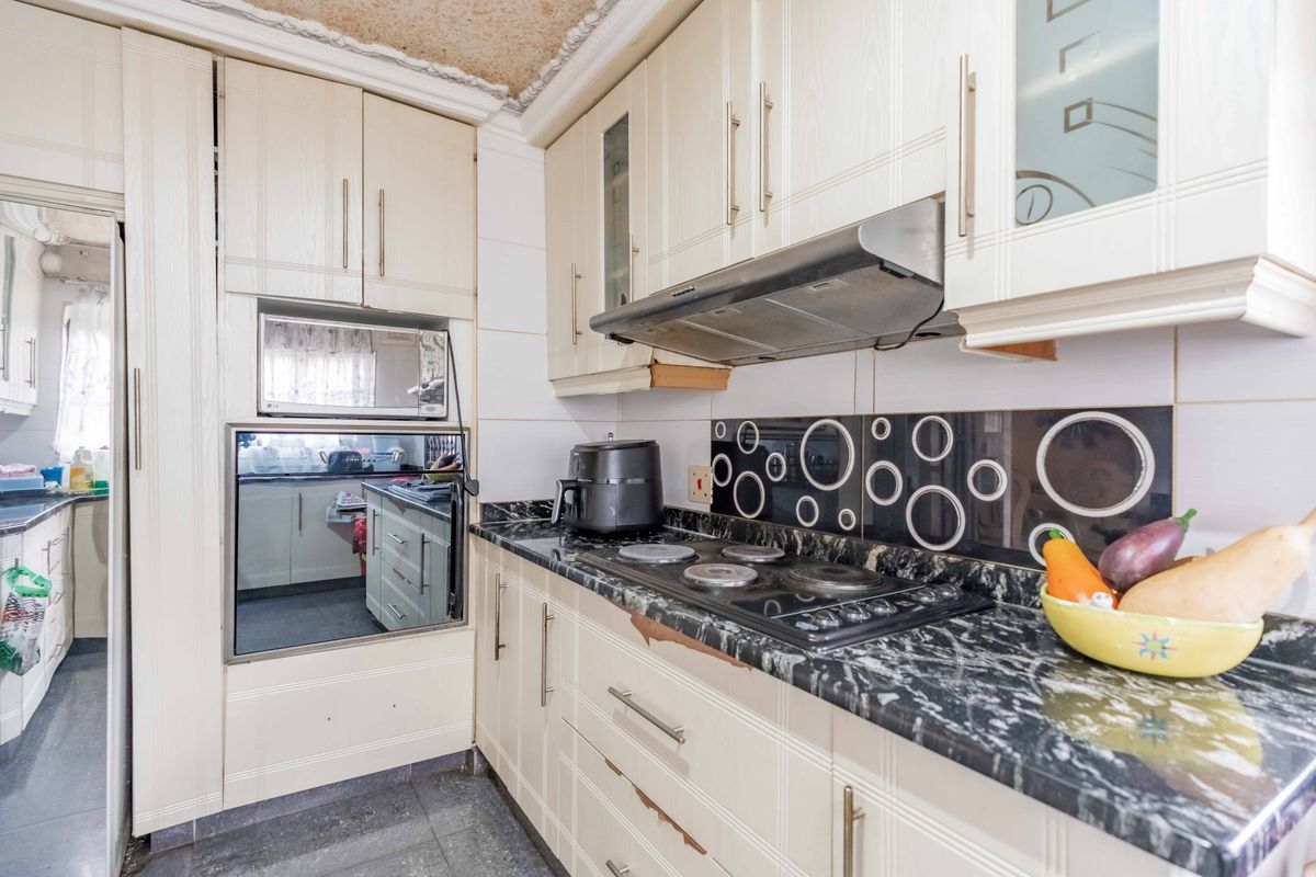 A functional kitchen featuring built-in cabinetry, integrated appliances including an oven and microwave, and a dark granite countertop with a decorative tiled backsplash.