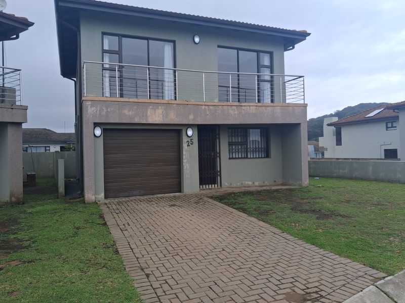Two-story residential property featuring a paved driveway, single garage, and an upper-level balcony with stainless steel railings.