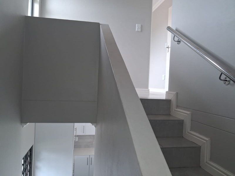 A clean, modern staircase featuring tiled steps and a sleek metal handrail, connecting the levels of the home.