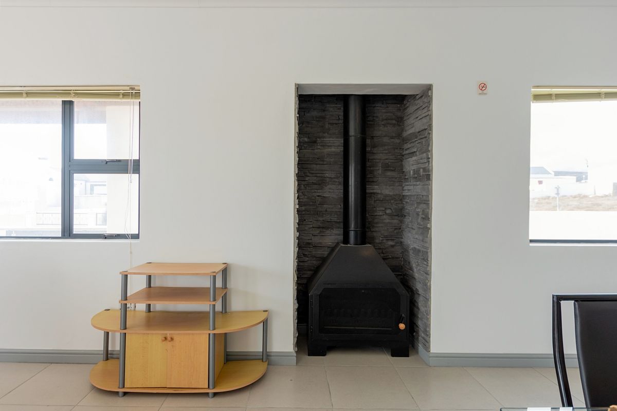 Living area featuring a built-in black metal fireplace with a stone-clad hearth and large windows providing natural light.