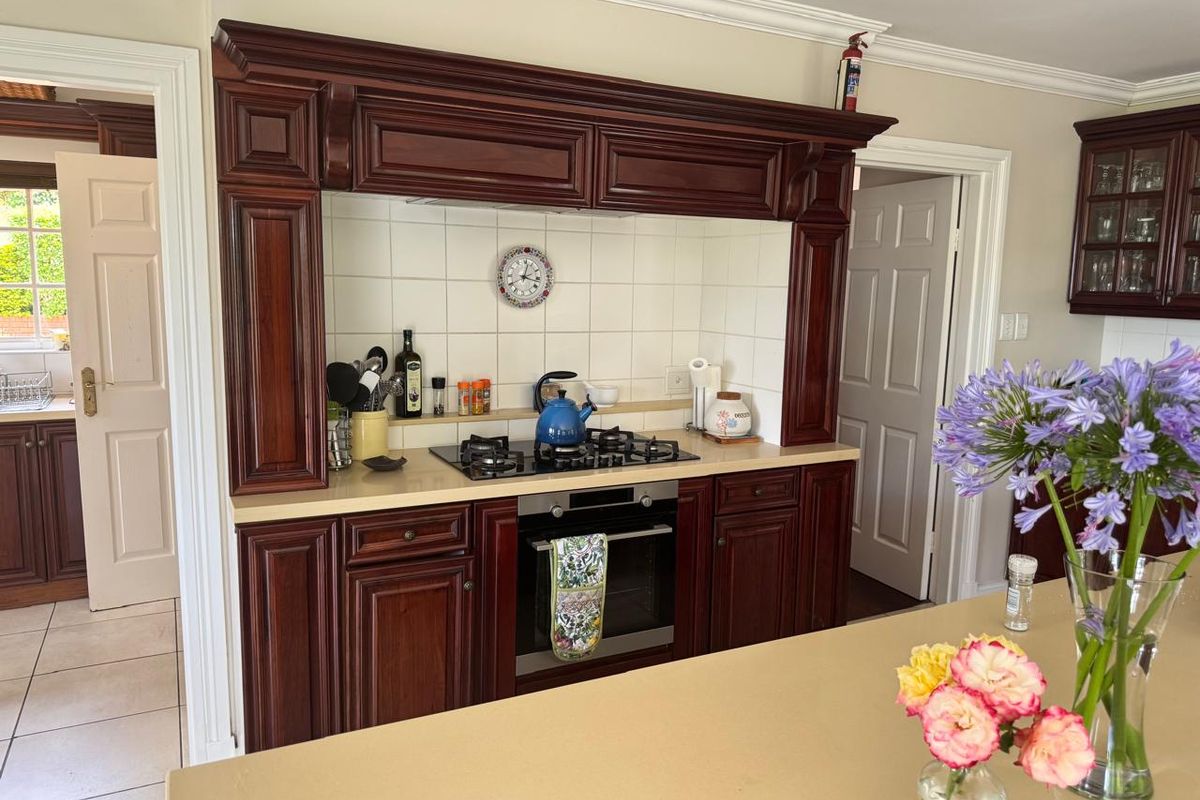 Traditional kitchen featuring dark wood cabinetry, a gas hob with integrated oven, stone countertops, and a central island, offering a classic aesthetic.