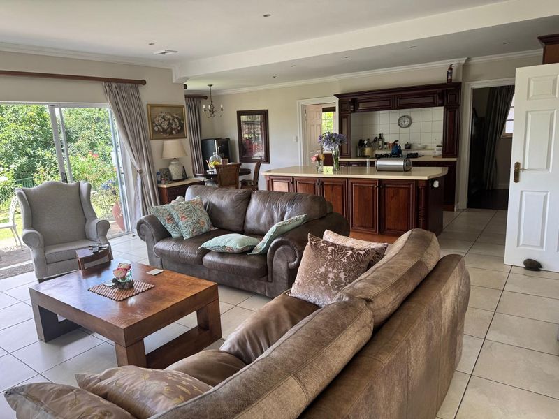 Spacious open-plan living area featuring a kitchen with a central island, tiled flooring, and large sliding doors providing access to the outdoor space.