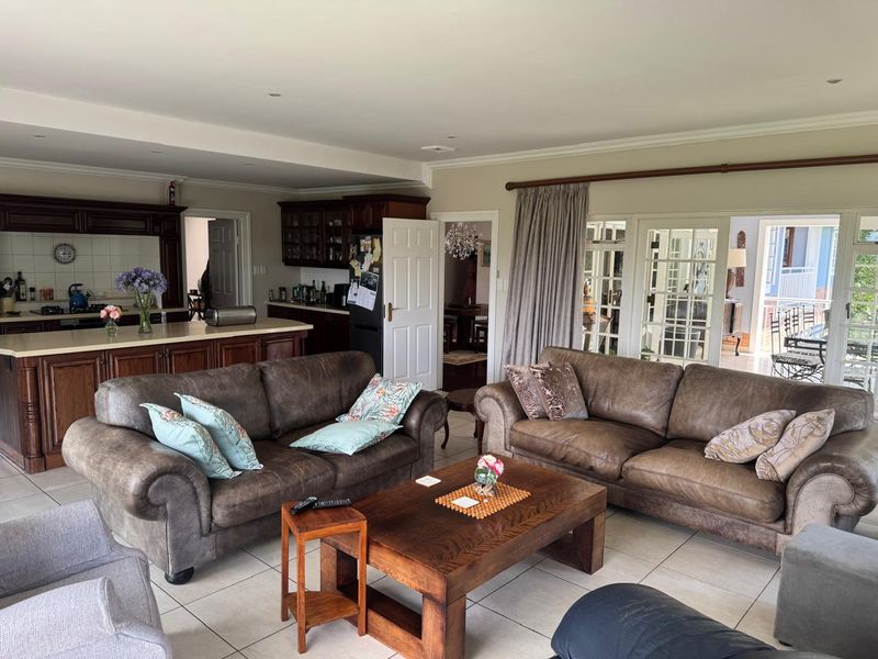 Spacious open-plan living area featuring a kitchen with island, tiled flooring, and direct access to the patio through classic french doors.