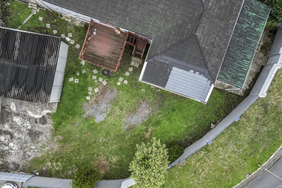 Aerial view of the property rear garden featuring a timber deck, lawn area, and a detached structure with a concrete paved section.
