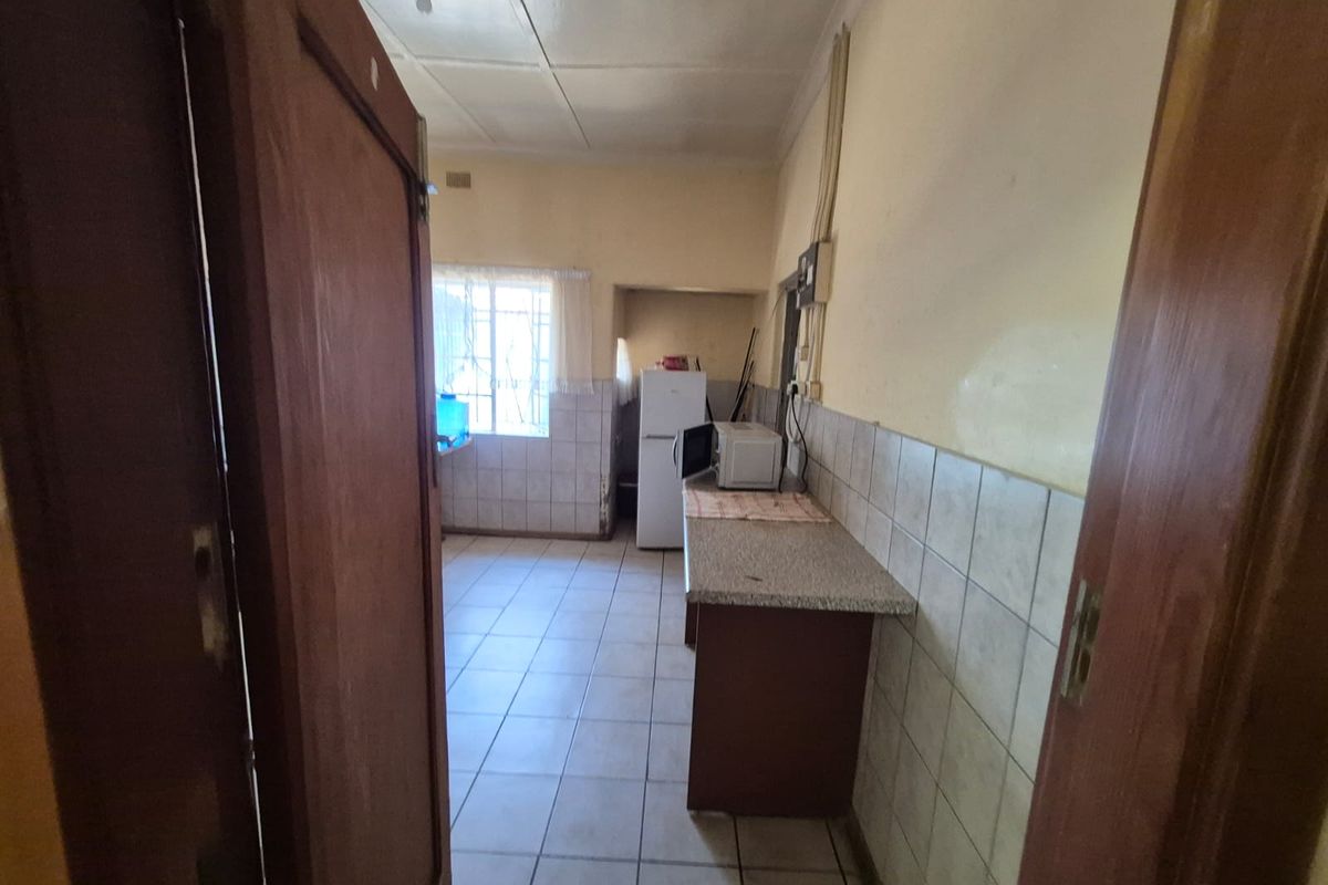 A functional kitchen space featuring tiled flooring, tiled splashbacks, and laminate countertops, offering a practical layout ready for modernization and cosmetic updates.