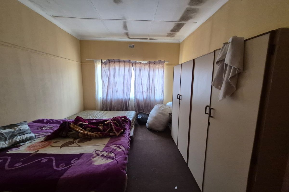 A bedroom featuring built-in cupboards and visible ceiling water damage, requiring maintenance and cosmetic updates to improve the living space.