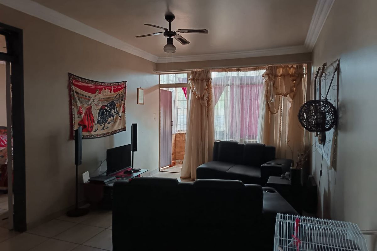 A living room featuring tiled flooring, crown molding, a ceiling fan, and a sliding glass door leading to an outdoor area.