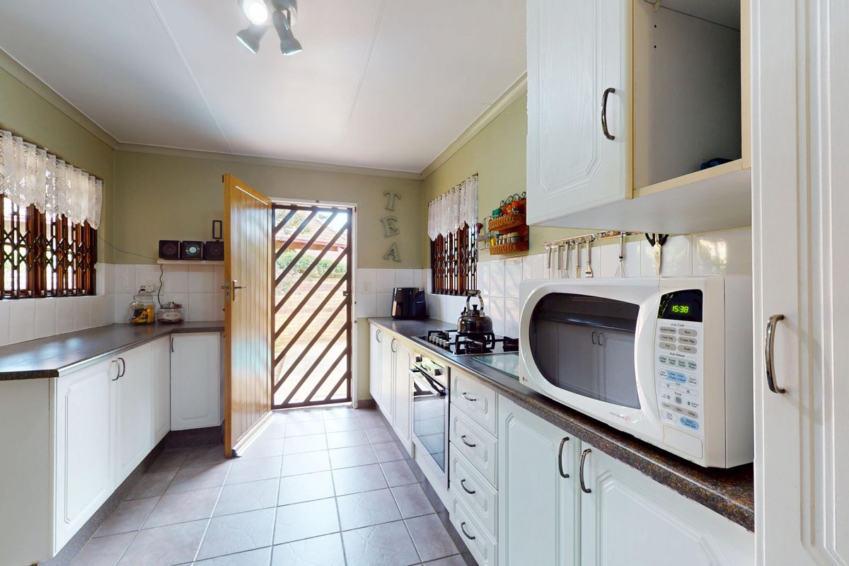 A functional kitchen featuring white cabinetry, laminate countertops, tiled backsplash, and built-in cooking appliances with direct access to the exterior.