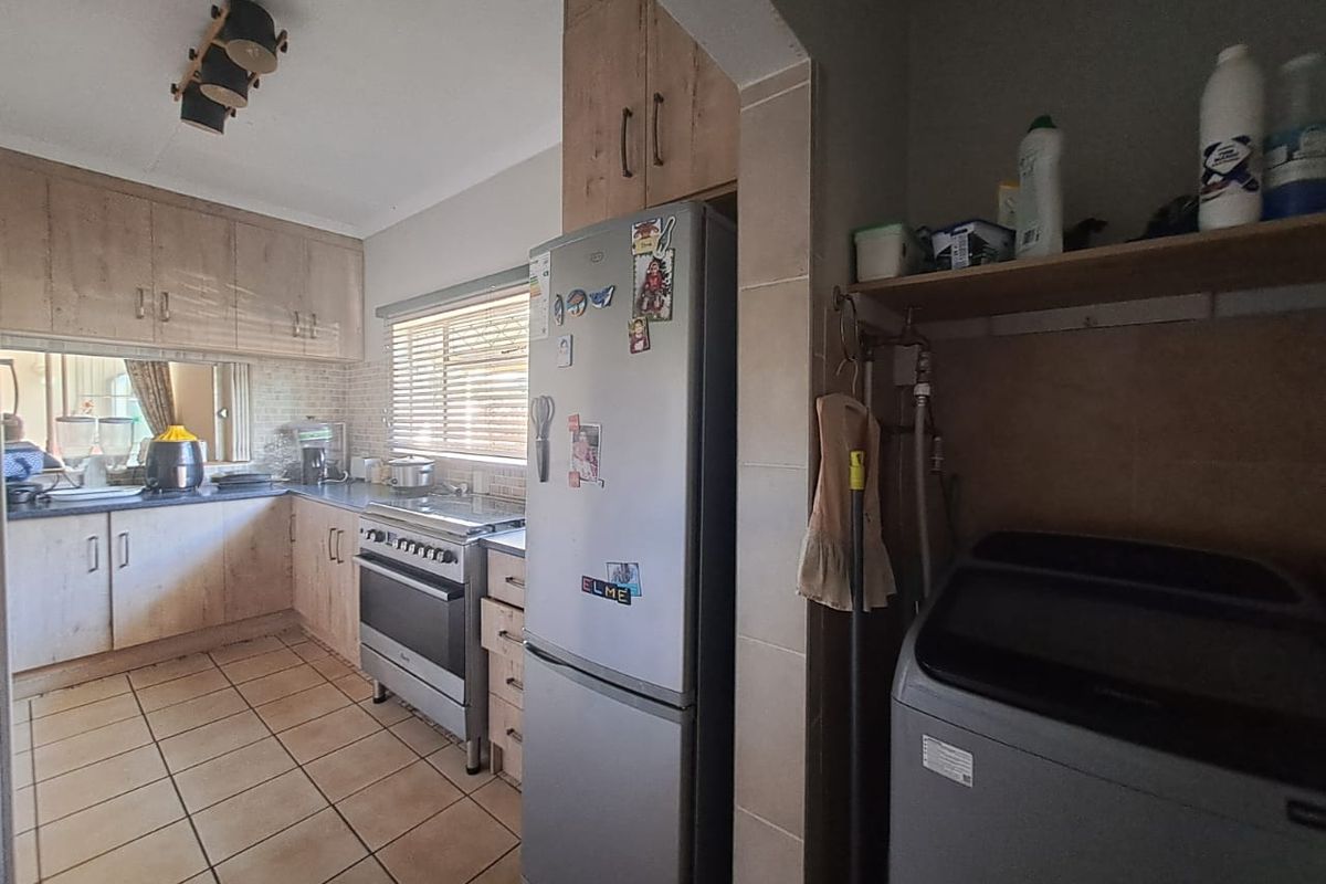 Functional kitchen featuring light wood-finish cabinetry, tiled flooring, and a dedicated laundry area with plumbing connections.