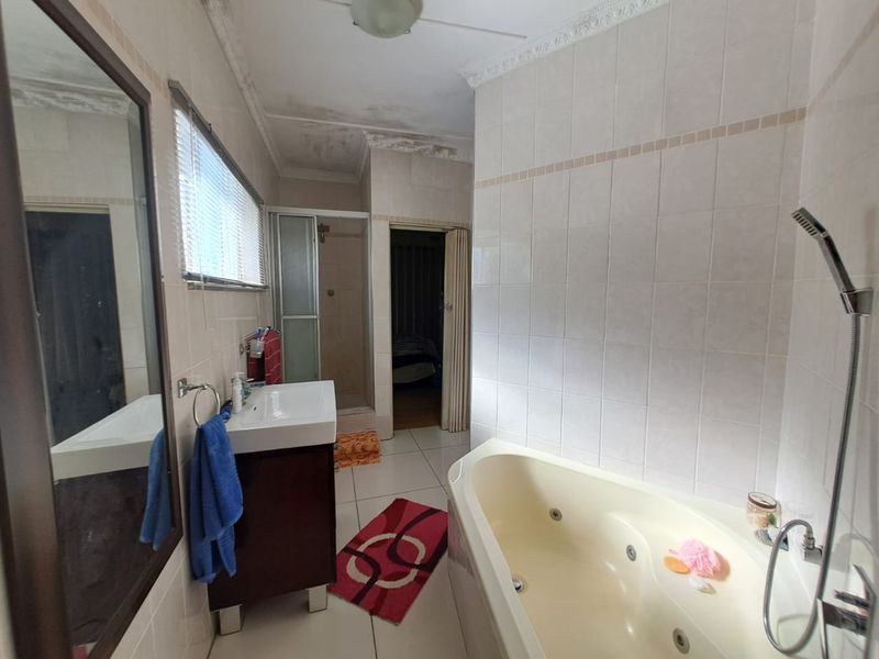 Bathroom featuring a corner spa bath, shower enclosure, and vanity cabinet, with visible water damage on the ceiling requiring maintenance.