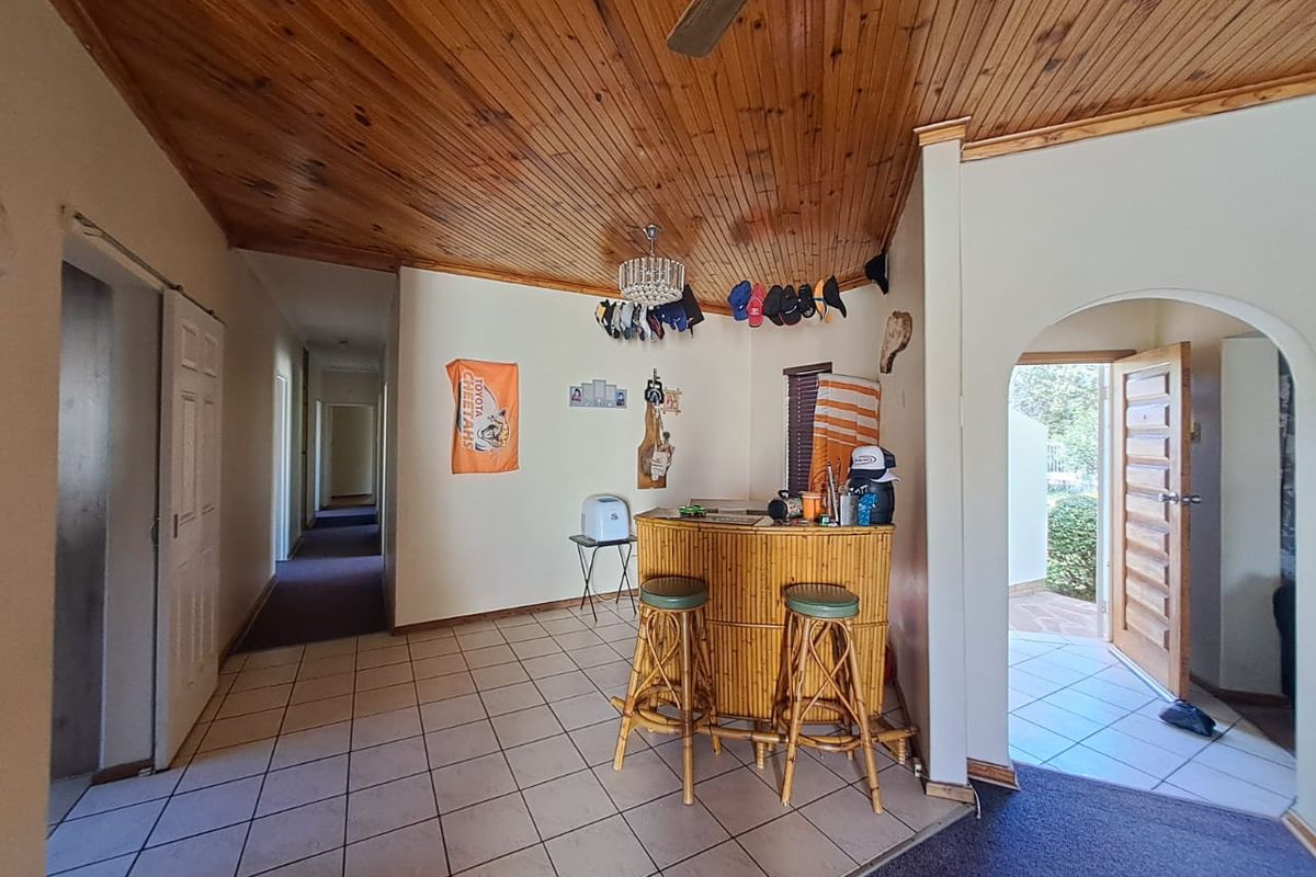 Living area featuring a timber tongue and groove ceiling, ceramic tiled flooring, and an arched entryway leading to the exterior.