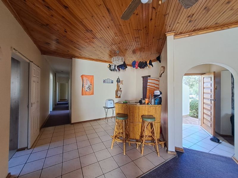 Living area featuring a timber tongue and groove ceiling, ceramic tiled flooring, and an arched entryway leading to the exterior.