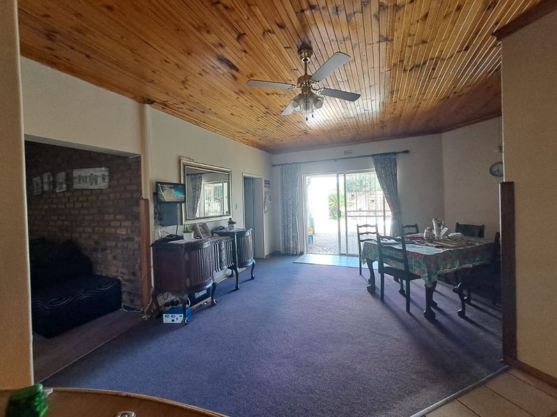 Open plan living and dining area featuring a timber ceiling, exposed brick accent wall, and sliding door access to the exterior.