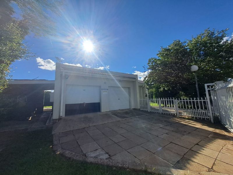 Exterior view of a double garage with a paved driveway and secure perimeter fencing.