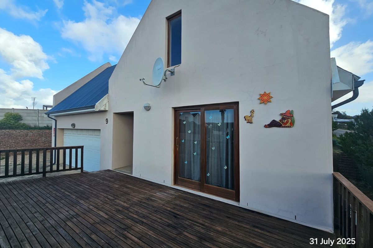 Exterior view of the property featuring a timber deck, sliding glass doors, and a garage entrance.