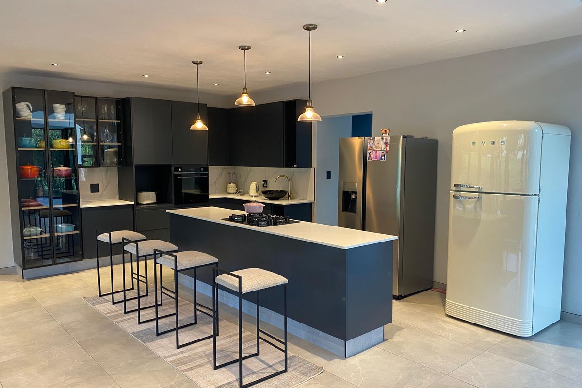 Modern kitchen featuring dark cabinetry, a central island with a gas hob, stone countertops, and high-quality finishes throughout.