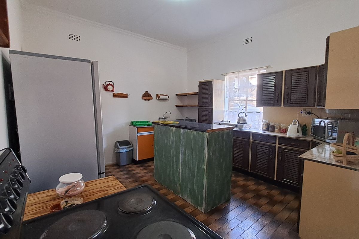 A functional kitchen featuring built-in cabinetry, a central island, and tiled flooring, offering potential for a modern renovation.
