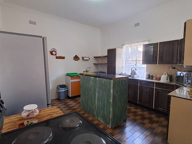 A functional kitchen featuring built-in cabinetry, a central island, and tiled flooring, offering potential for a modern renovation.