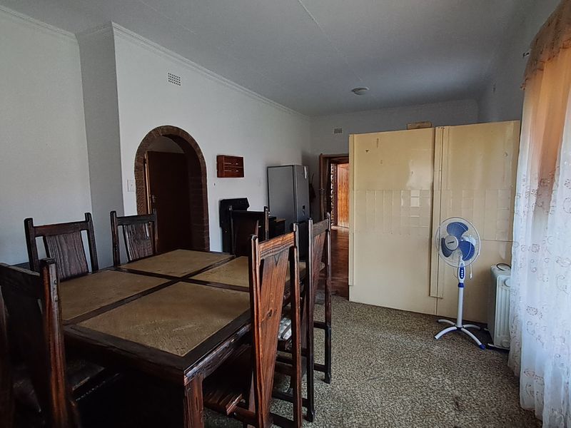 Dining room area featuring a brick archway, carpeted flooring, and a tiled partition wall, offering a functional space for family meals.