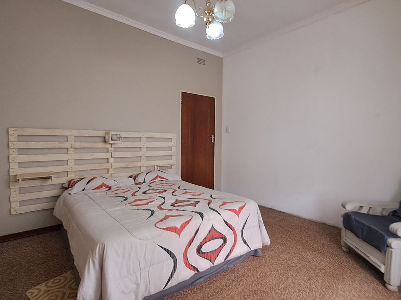 A bedroom featuring built-in cupboards, carpeted flooring, and a central ceiling light fixture.