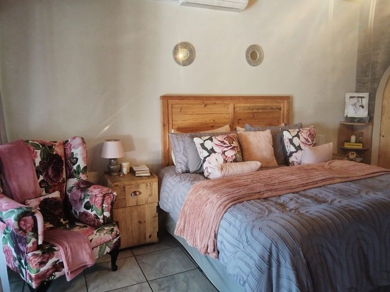 A cozy bedroom featuring tiled flooring and a wall-mounted air conditioning unit.