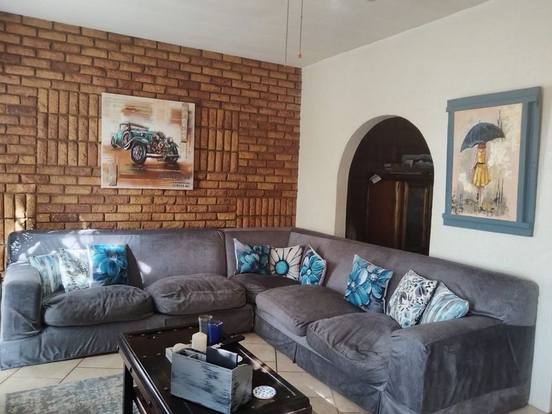 A cozy living room featuring a prominent exposed brick feature wall, tiled flooring, and a classic arched doorway leading to an adjacent space.