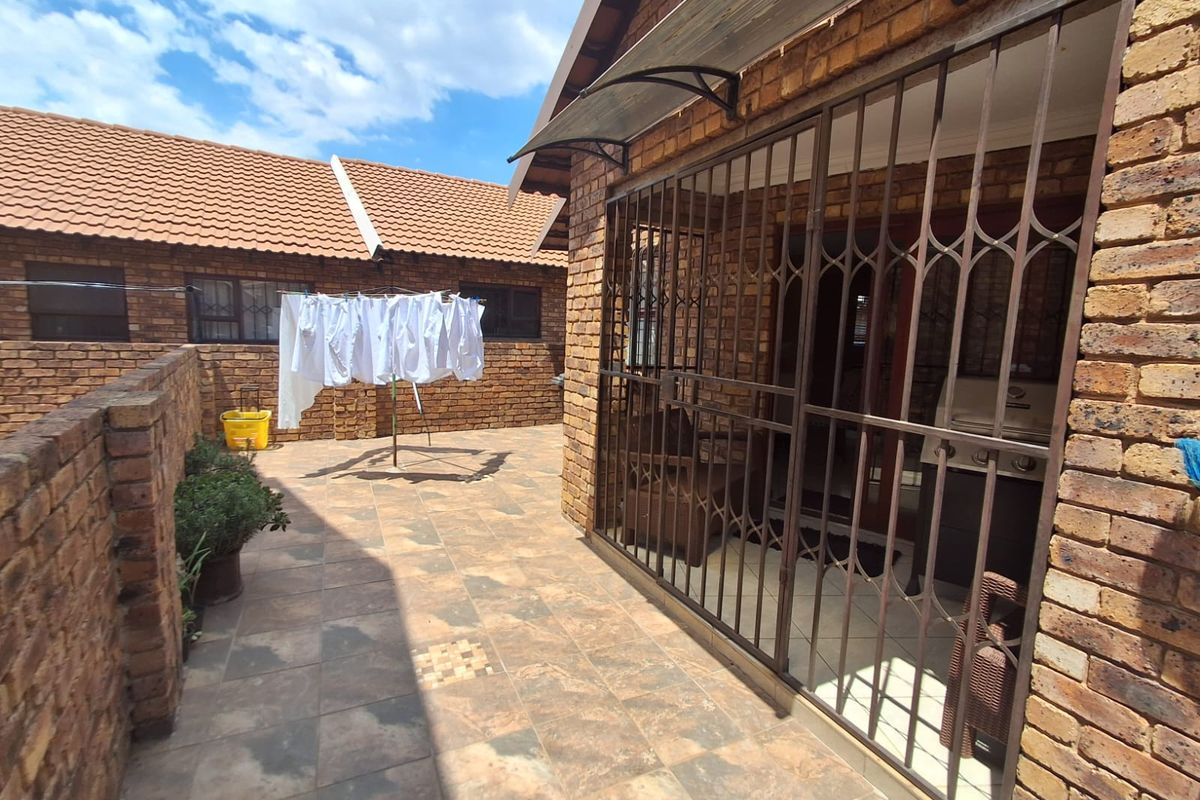 A private rear courtyard featuring face brick walls, tiled flooring, and a secure entrance with a metal security gate.
