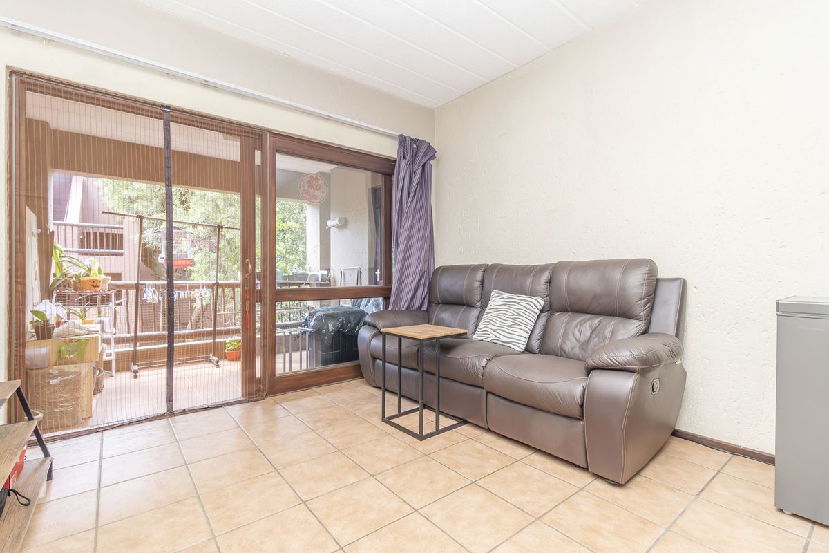 A living room featuring tiled flooring and a large sliding glass door providing access to an outdoor balcony area.