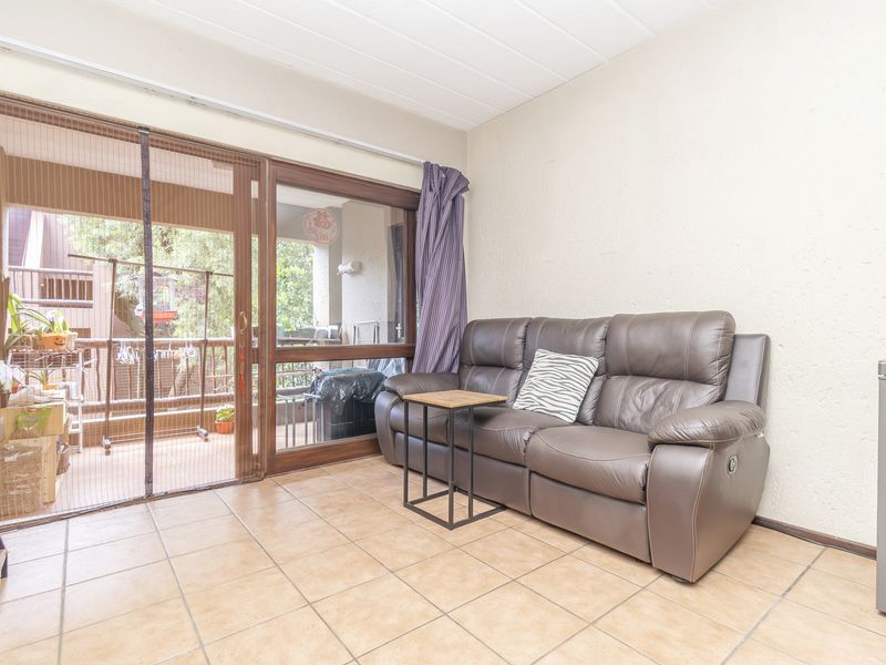 A living room featuring tiled flooring and a large sliding glass door providing access to an outdoor balcony area.