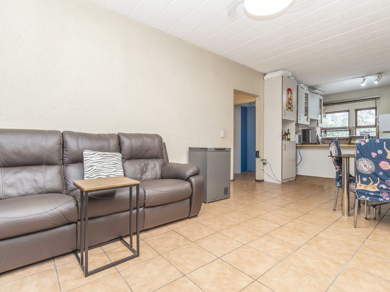 Open-plan living and kitchen area featuring tiled flooring and functional built-in cabinetry, offering a versatile space for daily living and dining.