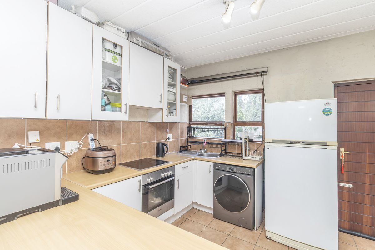 A functional kitchen featuring white cabinetry, laminate countertops, tiled backsplash, and built-in oven and hob, with space for laundry appliances.