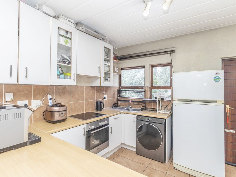 A functional kitchen featuring white cabinetry, laminate countertops, tiled backsplash, and built-in oven and hob, with space for laundry appliances.