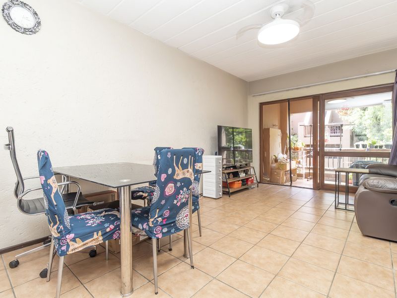 Open plan living and dining area featuring tiled flooring, a ceiling fan, and direct access to an outdoor balcony through sliding glass doors.