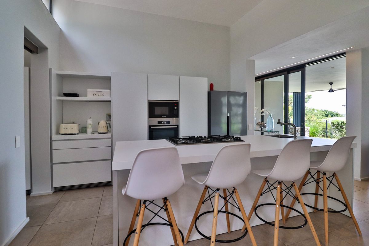 Modern kitchen featuring a central island with integrated gas cooktop, built-in appliances, and seamless access to an outdoor patio area.