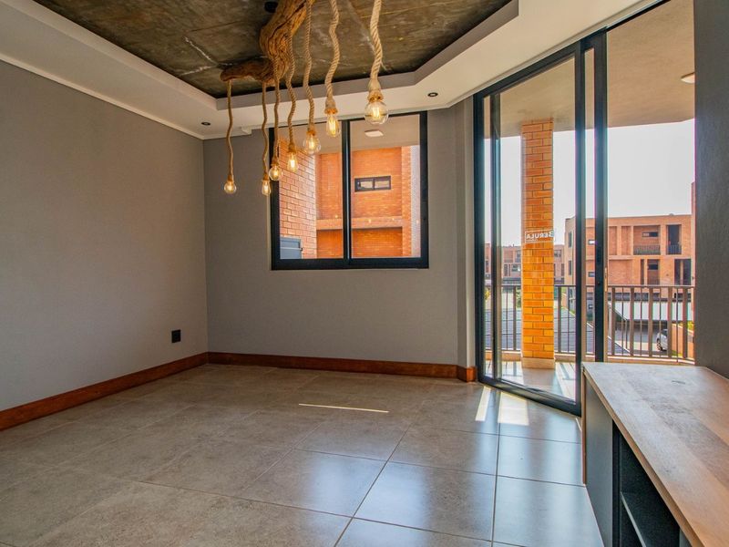 Modern living area featuring tiled floors, exposed concrete ceiling, and large sliding glass doors opening onto a private balcony.