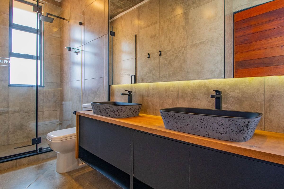 Modern bathroom featuring a double vanity with stone vessel sinks, a walk-in shower with glass screen, and contemporary tiled finishes.
