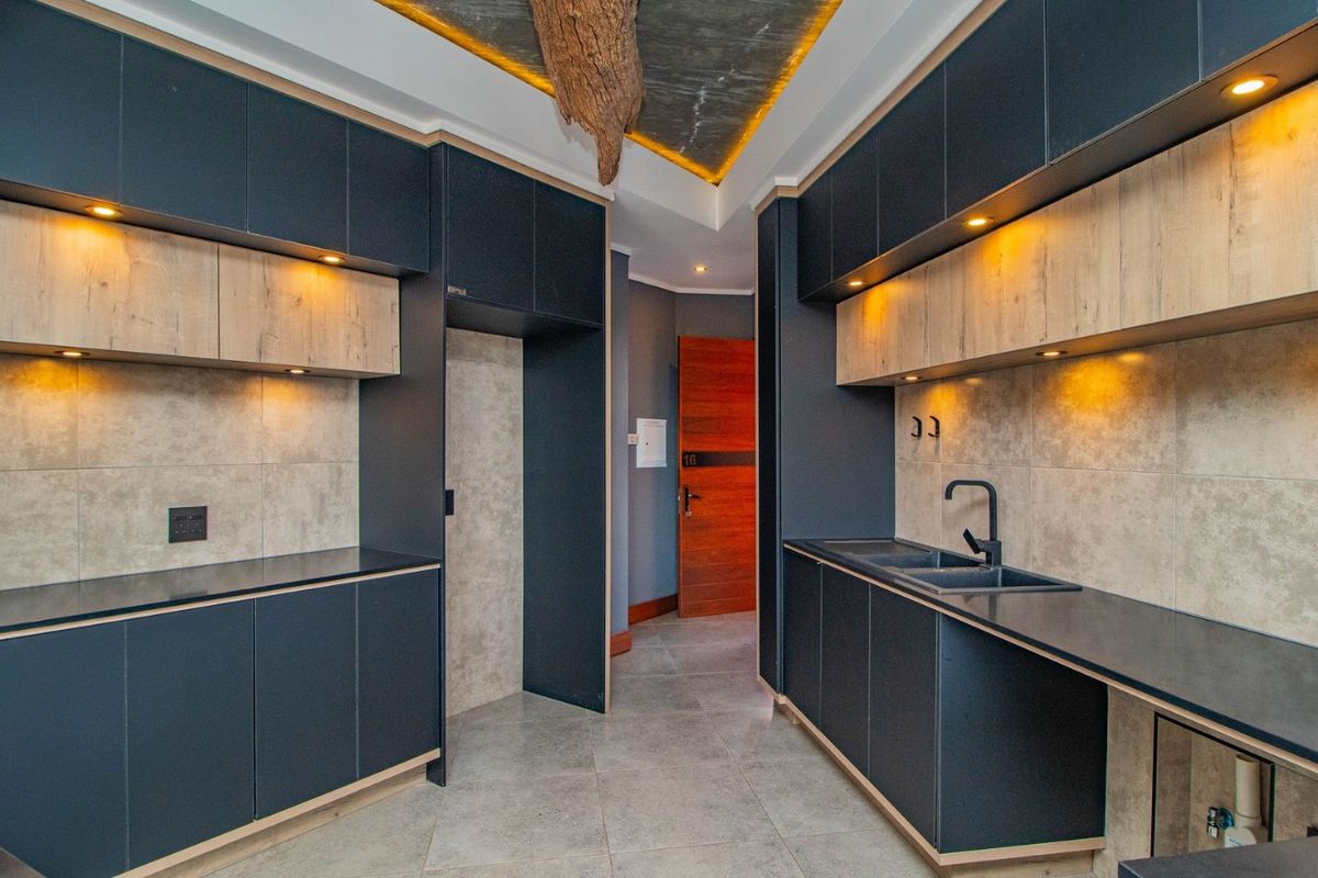Modern kitchen featuring dark matte cabinetry, light wood accents, stone countertops, integrated appliance spaces, and contemporary recessed lighting.