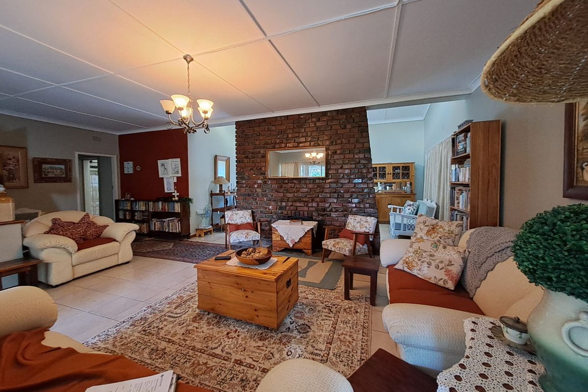 Spacious living room featuring an exposed brick fireplace, tiled flooring, and classic ceiling tiles, offering a warm and traditional atmosphere.